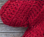 Zoomed In A wooden background with a red knitted objectMitten 