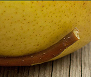 Zoomed In A fruit with green skin on it and a stem on the bottom Pear